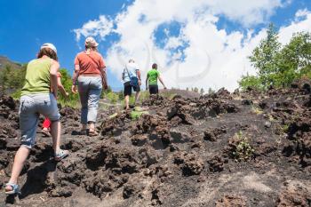 ETNA, ITALY - JULY 1, 2011 - tourists climb to old crater of Etna volcano on hardened lava flow. Mount Etna is active volcano on the east coast of Sicily, the tallest active volcano in Europe
