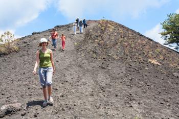 ETNA, ITALY - JULY 1, 2011 - tourists walk on ridge between old crater of Etna mount. Mount Etna is active volcano on the east coast of Sicily, the tallest active volcano in Europe