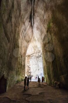 SYRACUSE, ITALY - JULY 3, 2011: people in Orecchio di Dionisio (Ear of Dionysius) ancient cave in Temenites Hill in Latomie del Paradiso area of Archaeological Park of Syracuse city in Sicily