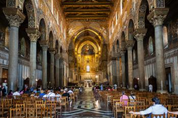 MONREALE, ITALY - JUNE 25, 2011: visitors indoor of Duomo di Monreale in Sicily. The cathedral of Monreale is one of the greatest examples of Norman architecture, it was begun in 1174