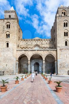 CEFALU, ITALY - JUNE 25, 2011: tourists near entrance in Duomo di Cefalu in Sicily. Cathedral - Basilica of Cefalu was erected in 1131 in the Norman architectural style
