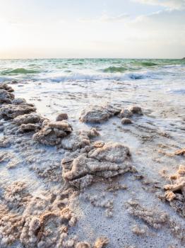 Travel to Middle East country Kingdom of Jordan - crystals of salt on coast of Dead Sea in winter evening