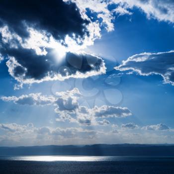 Travel to Middle East country Kingdom of Jordan - sunlight passes through dark blue clouds over Dead Sea in winter evening