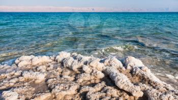Travel to Middle East country Kingdom of Jordan - pieces of salt close up on beach of Dead Sea in sunny winter day