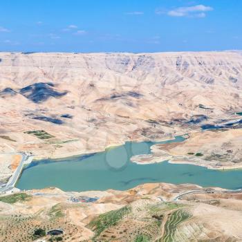 Travel to Middle East country Kingdom of Jordan - above view of Wadi Mujib river and Al Mujib dam from King's highway in winter