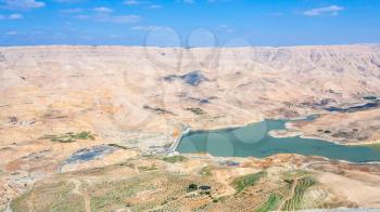 Travel to Middle East country Kingdom of Jordan - above view of valley of Wadi Mujib river and Al Mujib dam from King's highway in winter