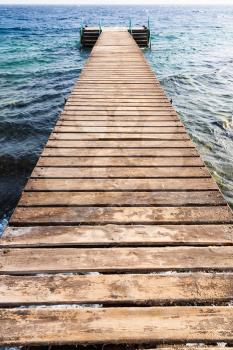Travel to Middle East country Kingdom of Jordan - wooden pier on Coral beach of Red Sea in Aqaba city in winter season