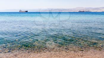 Travel to Middle East country Kingdom of Jordan - clean water near urban beach of Aqaba city in Gulf of Aqaba on Red Sea in winter morning