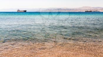 Travel to Middle East country Kingdom of Jordan - clear water near urban beach of Aqaba town in Gulf of Aqaba on Red Sea in winter morning