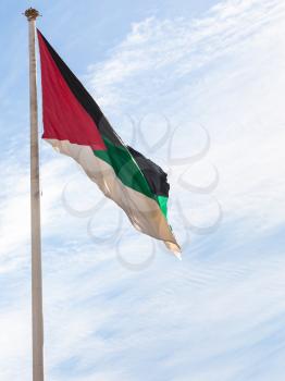 Travel to Middle East country Kingdom of Jordan - Flag of the Arab Revolt fluttering by wind in Aqaba city with blue sky with white clouds in background