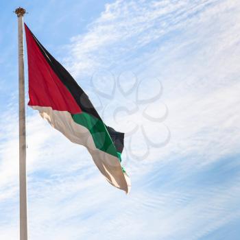 Travel to Middle East country Kingdom of Jordan - Flag of the Arab Revolt in Aqaba city with blue sky with white clouds in background