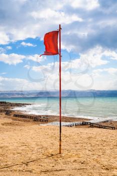 Travel to Middle East country Kingdom of Jordan - red flag on beach of Dead Sea in sunny winter day