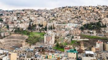 AMMAN, JORDAN - FEBRUARY 18, 2012: skyline of Amman city with ancient Roman theater from citadel in winter. The Amphitheatre was built the Roman period when the city was known as Philadelphia