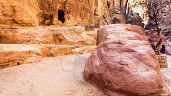 PETRA, JORDAN - FEBRUARY 21, 2012: tourists near caves in Al Siq gorge to ancient Petra town in winter. Rock-cut town Petra was established about 312 BC as the capital city of the Arab Nabataean