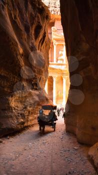 PETRA, JORDAN - FEBRUARY 21, 2012: bedouin carriage and view of al-Khazneh temple from Al Siq in Petra town. Rock-cut town Petra was established about 312 BC as the capital city of the Arab Nabataean