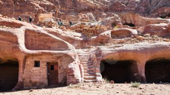 PETRA, JORDAN - FEBRUARY 21, 2012: tourists and bedouin house in ancient cave in Petra town. Rock-cut town Petra was established about 312 BC as the capital city of the Arab Nabataean