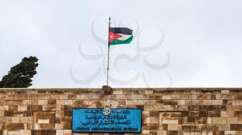 AMMAN, JORDAN - FEBRUARY 18, 2012: flag over Jordan Archaeological Museum at Amman Citadel in rainy day. Museum was built in 1951, it keeps artifacts from archaeological sites of Jordan
