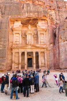 PETRA, JORDAN - FEBRUARY 21, 2012: Tourist in front of al-Khazneh temple (The Treasury) in Petra town. Rock-cut town Petra was established about 312 BC as the capital city of the Arab Nabataean