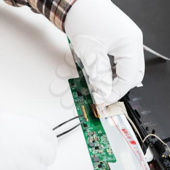 disassembling of laptop - serviceman in white gloves replaces LCD screen