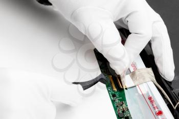 repairman in white gloves detaches the contacts of laptop screen