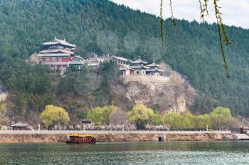 travel to China - view of temples on East Hill of Chinese Buddhist monument Longmen Grottoes (Dragon's Gate Grottoes, Longmen Caves) through Yi river in spring season