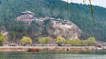 travel to China - view of pagodas on East Hill of Chinese Buddhist monument Longmen Grottoes (Dragon's Gate Grottoes, Longmen Caves) through Yi river in spring season