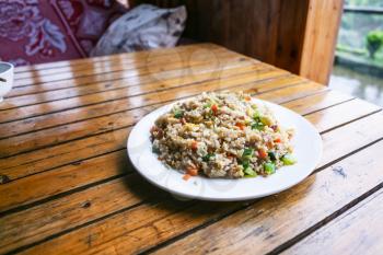 travel to China - portion of fried rice with vegetables on plate in rustic eatery in area Dazhai Longsheng Rice Terraces (Dragon's Backbone terrace, Longji Rice Terraces) country in spring