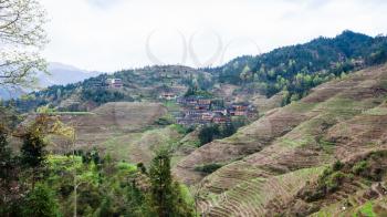 travel to China - view of Dazhai village on green hills in area Longsheng Rice Terraces (Longji Rice Terraces) in spring