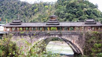 travel to China - exterior of Dong people style bridge in Jiangdi village over river in Longsheng Hot Springs National Forest Park of Xiangshan District in spring season
