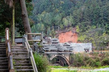 travel to China - steps on Wind and Rain Bridge and gardens near river in Chengyang village of Sanjiang Dong Autonomous County in spring season