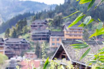 travel to China - green twig with leaves and and unfocused country houses in Chengyang village of Sanjiang Dong Autonomous County in spring season