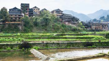 travel to China - view of terraced gardens and houses near irrigation canal in Chengyang village of Sanjiang Dong Autonomous County in spring season