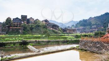 travel to China - view of terraced rice paddies and houses near irrigation canal in Chengyang village of Sanjiang Dong Autonomous County in spring season