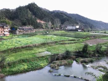 travel to China - view of gardens and rice fields near river in Chengyang village of Sanjiang Dong Autonomous County in spring evening