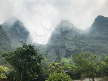 travel to China - gray clouds over green karst peaks in Yangshuo County in spring season