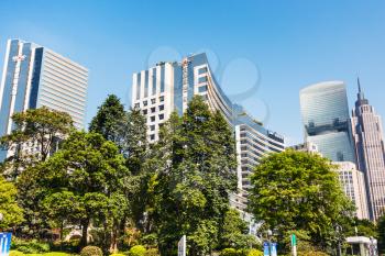 GUANGZHOU, CHINA - APRIL 1, 2017: green trees and skyscrapers in Zhujiang New Town of Guangzhou city in spring. Guangzhou is the third most-populous city in China with population about 13,5 mln