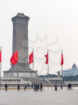 BEIJING, CHINA - MARCH 19, 2017: people and red flags near Monument to the People's Heroes on Tiananmen Square in spring. Tiananmen Square is central city square in Beijing