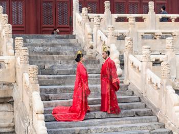 BEIJING, CHINA - MARCH 19, 2017: couple in traditional costumes on steps of Hall for Worship of Ancestors in Imperial Ancestral Temple (Taimiao) in Beijing Imperial city in spring.