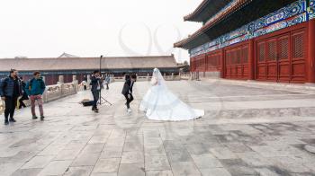 BEIJING, CHINA - MARCH 19, 2017: photographer and bride in photosession at courtyard of Imperial Ancestral Temple (Taimiao, Working People's Cultural Palace) in Beijing Imperial city in spring.