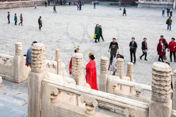 BEIJING, CHINA - MARCH 19, 2017: couple in red dresses and tourists on courtyard of Imperial Ancestral Temple (Taimiao, Working People's Cultural Palace) in Beijing Imperial city in spring