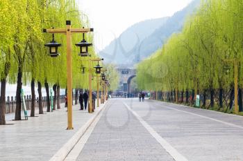 LUOYANG, CHINA - MARCH 20, 2017: visitors on Yidong road on embankment Yi river walk to Chinese Buddhist monument Longmen Grottoes (Dragon's Gate Grottoes, Longmen Caves) in spring
