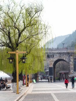 LUOYANG, CHINA - MARCH 20, 2017: people walk to entrance to Buddhist monument Longmen Grottoes (Longmen Shiku, Dragon's Gate Grottoes, Longmen Caves) under Bridge over Yi River (Yi He) in spring