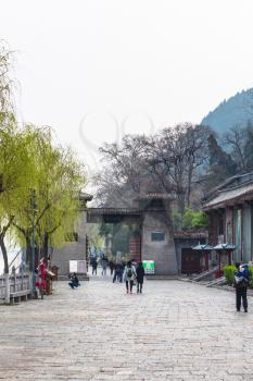 LUOYANG, CHINA - MARCH 20, 2017: tourists walk to gate to Buddhist monument Longmen Grottoes (Longmen Shiku, Dragon's Gate Grottoes, Longmen Caves) on waterfront Yi river in spring