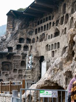LUOYANG, CHINA - MARCH 20, 2017: tourists near caves in Chinese Buddhist monument Longmen Grottoes (Longmen Caves). The complex was inscribed upon the UNESCO World Heritage List in 2000