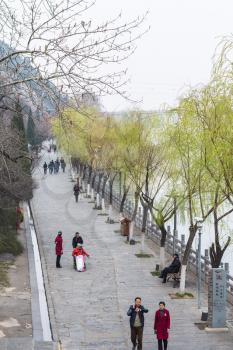 LUOYANG, CHINA - MARCH 20, 2017: visitors on embankment of Yi river on West Hill of Buddhist monument Longmen Grottoes (Longmen Shiku, Dragon's Gate Grottoes, Longmen Caves) in spring season