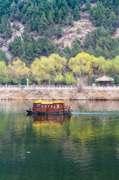 LUOYANG, CHINA - MARCH 20, 2017: passenger boat in Yi river between West and East Hills of Buddhist monument Longmen Grottoes (Longmen Shiku, Dragon's Gate Grottoes, Longmen Caves) in spring season
