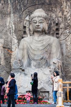 LUOYANG, CHINA - MARCH 20, 2017: visitors near The Big Vairocana statue in main Longmen Grottoes (Longmen Caves). The complex was inscribed upon the UNESCO World Heritage List in 2000