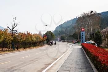 LUOYANG, CHINA - MARCH 20, 2017: visitors on road to area of Chinese Buddhist monument Longmen Grottoes (Dragon's Gate Grottoes, Longmen Caves) in valley Yi river in spring