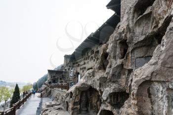 LUOYANG, CHINA - MARCH 20, 2017: people near caves and Grottoes in West Hill of Chinese Buddhist monument Longmen Grottoes. The complex was inscribed upon the UNESCO World Heritage List in 2000