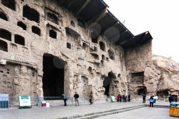 LUOYANG, CHINA - MARCH 20, 2017: tourists near hall in caves of West Hill of Chinese Buddhist monument Longmen Grottoes. The complex was inscribed upon the UNESCO World Heritage List in 2000